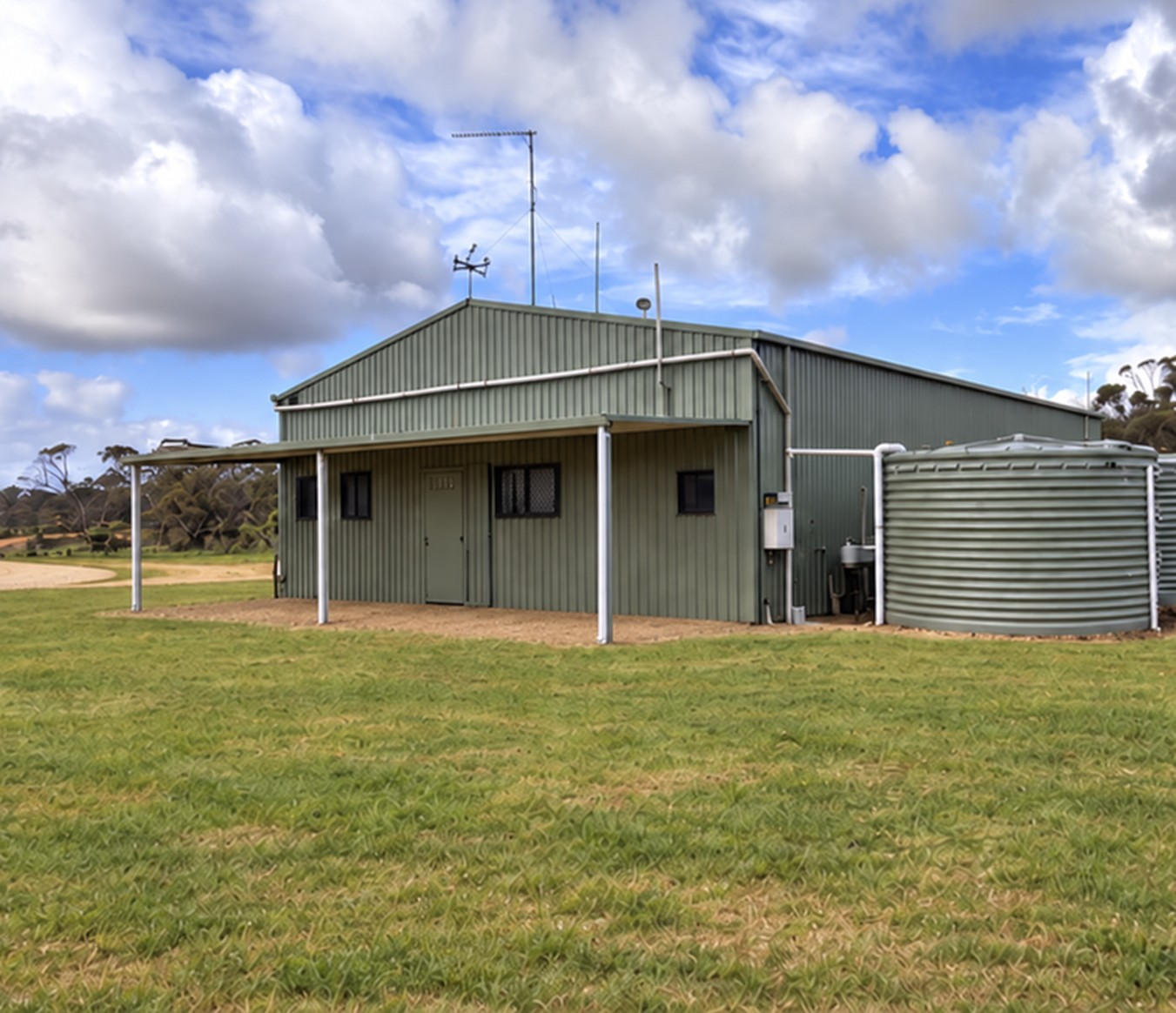 Green steel barn beside the property's rainwater tanks